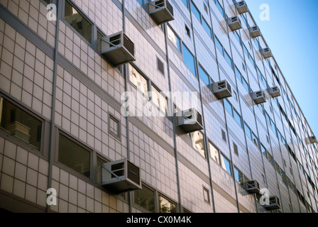 Air conditioners sprout from windows in a building in New York Stock Photo