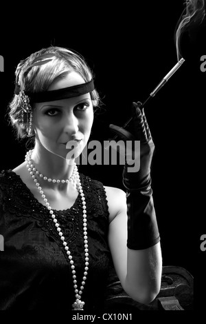 Woman in flapper dress in twenties style smoking a cigarette Stock Photo