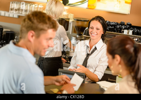 Couple paying bill at cafe cash desk smiling waitress bar Stock Photo