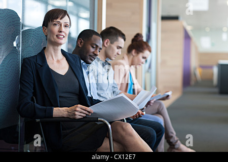 Four people sitting on chairs with documents Stock Photo