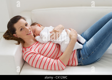 Woman and baby girl resting on sofa Stock Photo
