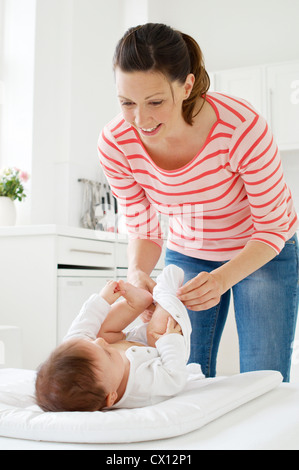 Mother changing baby daughter Stock Photo