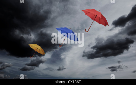 Three umbrellas floating through cloudy sky Stock Photo