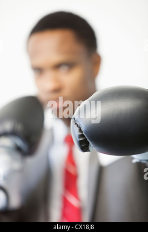 Businessman wearing boxing gloves with focus on gloves Stock Photo