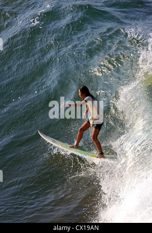 Local female surfer surfing at Batu Karas in West Java, Indonesia. Stock Photo