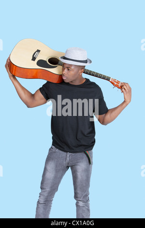 Young African American man carrying guitar over light blue background Stock Photo