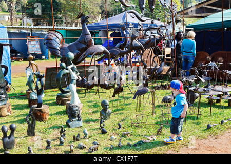 A young boy looks at a display of soapstone carvings and metal sculptures Stock Photo