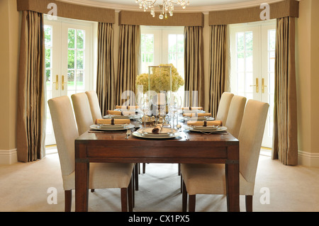 The dining room of an interior designed luxury house with a set table seen from the end with chairs. Stock Photo