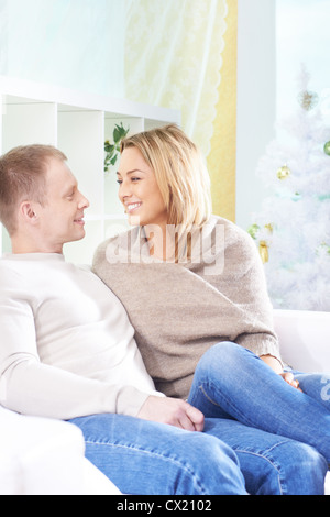 Happy couple sitting on sofa and looking at one another Stock Photo