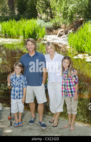 Full length portrait of couple with children standing against lake Stock Photo