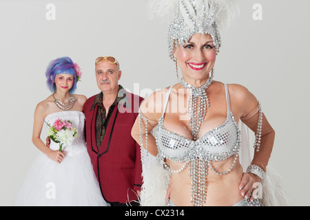 Portrait of senior showgirl with father and daughter in wedding dress in background Stock Photo