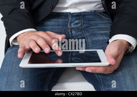 A Man with blue jeans working on a tablet pc with he's hand Stock Photo