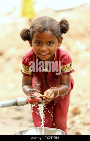 Young Indian girl drinking and washing from a hand water pump in rural ...