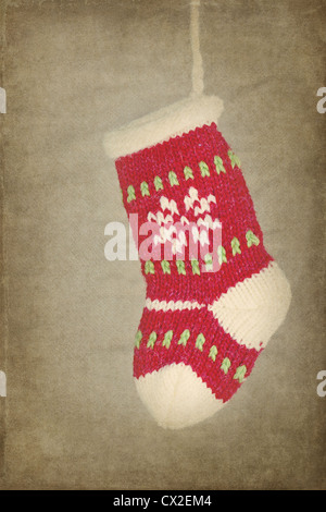 Red cute knitted Christmas sock / stocking hanging on rustic vintage textured background Stock Photo