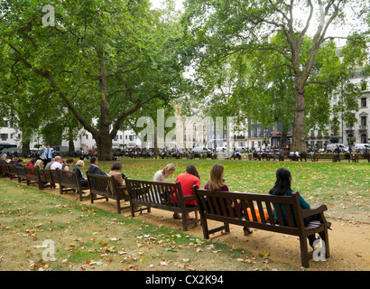 Berkeley Square in Westminster London.  Lots of people sat outside eating their lunch. Stock Photo