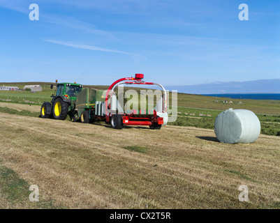 dh Tractor HARVESTING UK John Deere tractor baling rapping field harvesting bale making machinery round wrapper hay farm baler roller machine Stock Photo