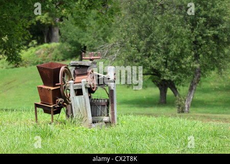 A rundown old apple cider press sits in front of the orchard. Stock Photo