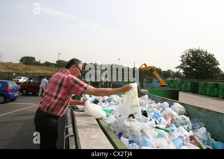 Man throwing a bag of plastic items into a large container at a recycling centre in Barnet Hertfordshire UK Stock Photo