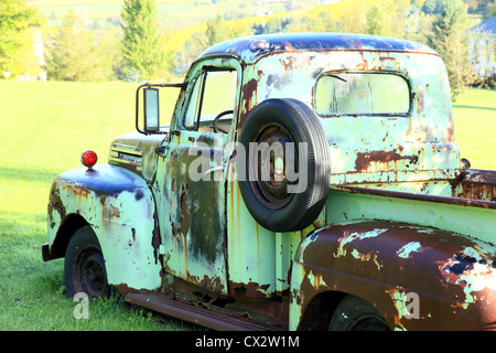 A classic Ford pickup sits in a field. Stock Photo