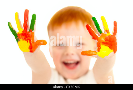 Adorable red-haired boy with focus on hands painted in bright colors Stock Photo