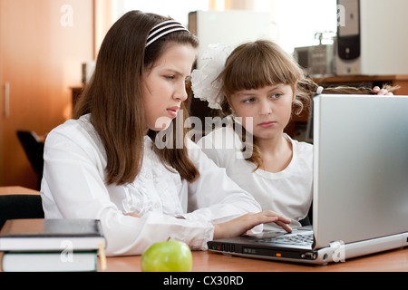 Two schoolgirls performs task using notebook Stock Photo