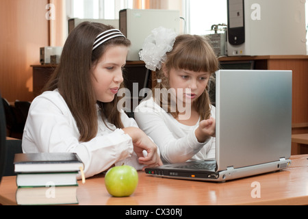 Two schoolgirls performs task using notebook Stock Photo