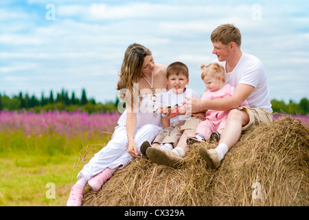 Happy family launching toy aircraft model sitting on haystack together Stock Photo