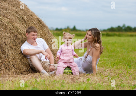 Happy family in haystack or hayrick with watermelon Stock Photo