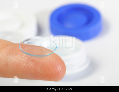 Contact lens on finger with containers on background