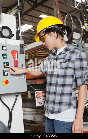 Female industrial worker operating manufacturing machine at factory Stock Photo