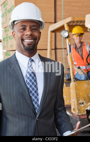Portrait of African American male engineer smiling with female worker in background Stock Photo