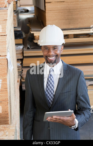 Portrait of African American male contractor using tablet PC with wooden planks in background Stock Photo