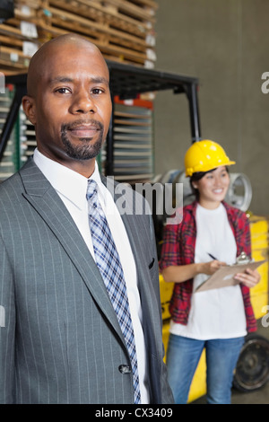 Portrait of confident African American male businessman with female worker standing in background Stock Photo