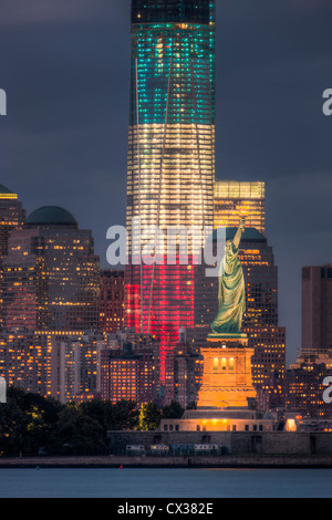 Two symbols of freedom, the Statue of Liberty and the Freedom Tower, in red, white and blue lights, illuminated at twilight in New York City.