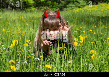 little devil girl in a green dandelion field Stock Photo