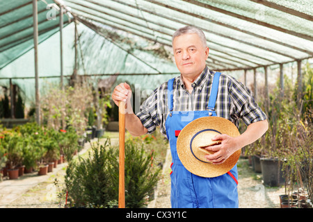 Male worker holding a shovel and posing in a flower garden Stock Photo