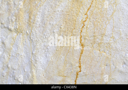 Whitewashed concrete wall showing symptoms of rust stains from iron pipework. Weathered paint texture, cracked wall. Stock Photo