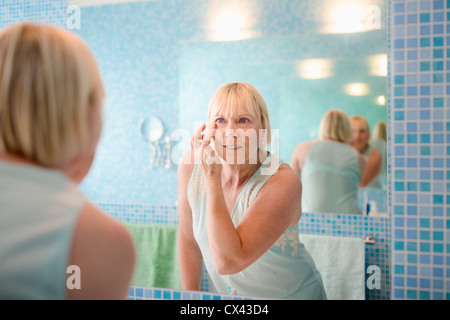 Female beauty, senior caucasian woman applying lotion on face in bathroom at home Stock Photo