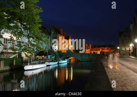 Ghostly figures walking along the canal in Brugge at night Stock Photo