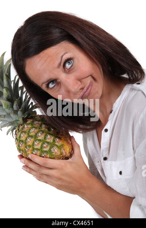 Woman listening to pineapple Stock Photo