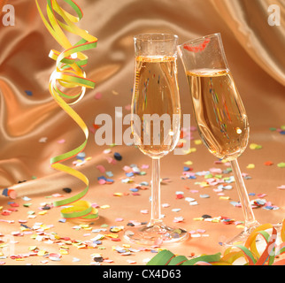 party background with filled champagne glasses in floating satin back with streamers and confetti Stock Photo