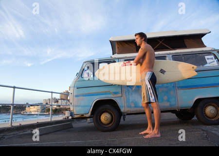 Man holding surfboard next to camper van. Bondi Beach, Sydney, New South Wales, AUSTRALIA Stock Photo