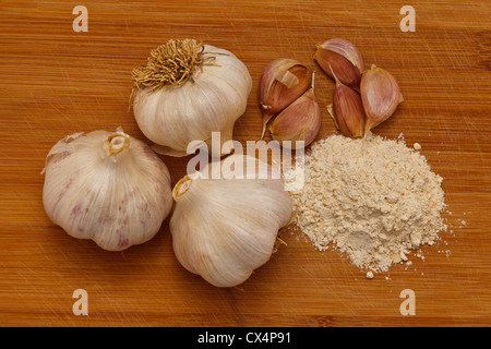 Homegrown garlic bulbs, cloves, and the resulting garlic powder on a wooden cutting board. Stock Photo