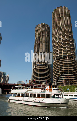 Marina City, also known as the corn cob buildings on the Chicago River with a cruise boat in the foreground on a sunny day. Stock Photo