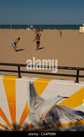 People playing badminton on Oak Street Beach on a sunny day with public art in the foreground. Stock Photo