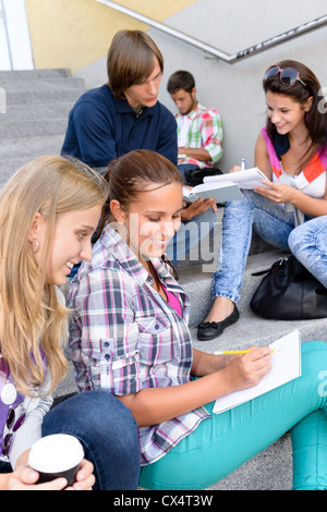 Students sitting on school steps writing studying teens college high-school Stock Photo
