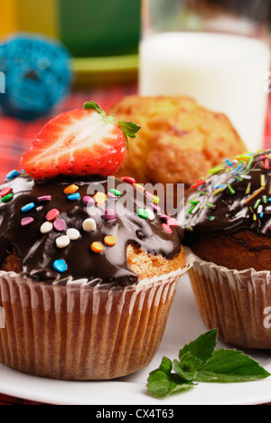Three muffins with sprinkles on the plate with a glass of milk Stock Photo