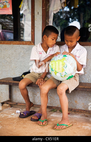 Thai schoolchildren studying a world globe. Mae Hong Son, Mae Hong Son, Thailand Stock Photo