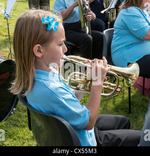 little girl playing trumpet on a gray background Stock Photo