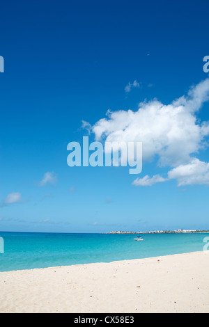 Beach scenery. Vertical landscape with white sand, turquoise waters, and a blue sky with drifting clouds. Stock Photo